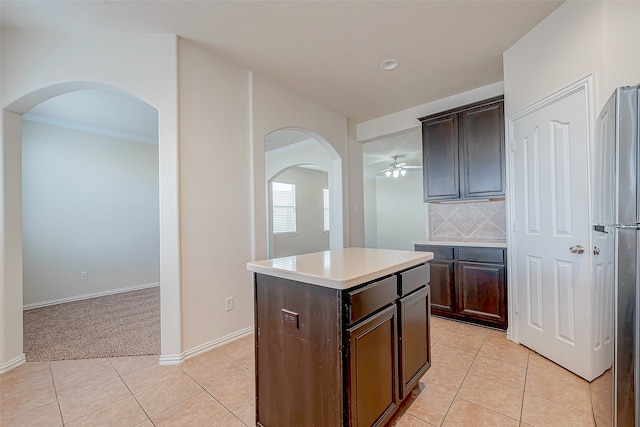 kitchen featuring dark brown cabinets, a kitchen island, light tile patterned flooring, and tasteful backsplash