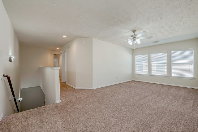 carpeted spare room with ceiling fan and a textured ceiling