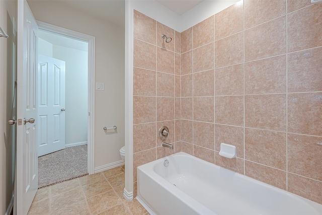 bathroom featuring tile patterned flooring, tiled shower / bath combo, and toilet