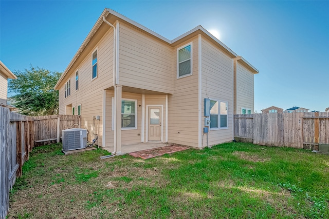 rear view of house with a lawn, cooling unit, and a patio