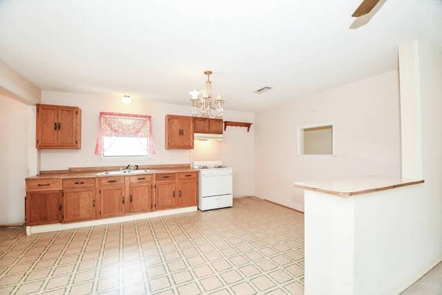 kitchen featuring sink, hanging light fixtures, a notable chandelier, kitchen peninsula, and white stove