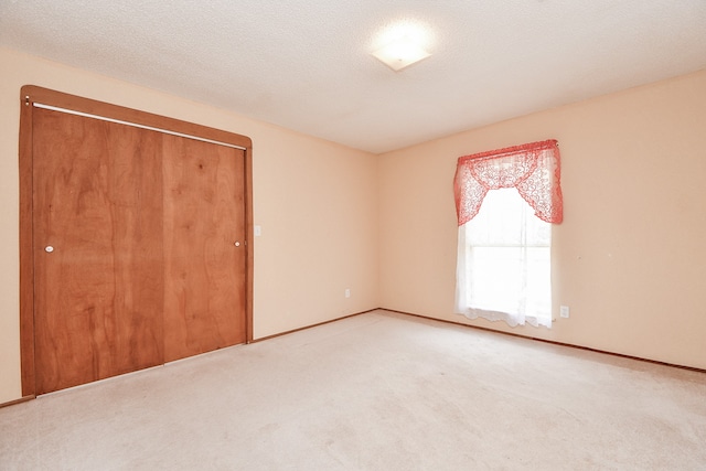 unfurnished bedroom with a closet, light colored carpet, and a textured ceiling