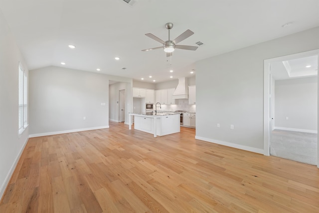 unfurnished living room featuring light hardwood / wood-style floors, ceiling fan, lofted ceiling, and sink