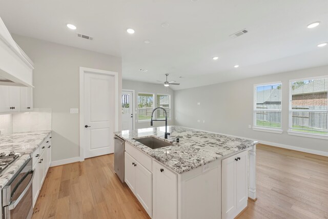 kitchen featuring appliances with stainless steel finishes, ceiling fan, sink, white cabinets, and an island with sink