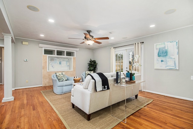 living room with ceiling fan, ornate columns, ornamental molding, and light hardwood / wood-style flooring