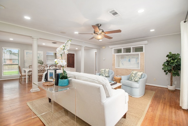 living room with light wood-type flooring, ornate columns, ceiling fan, and ornamental molding