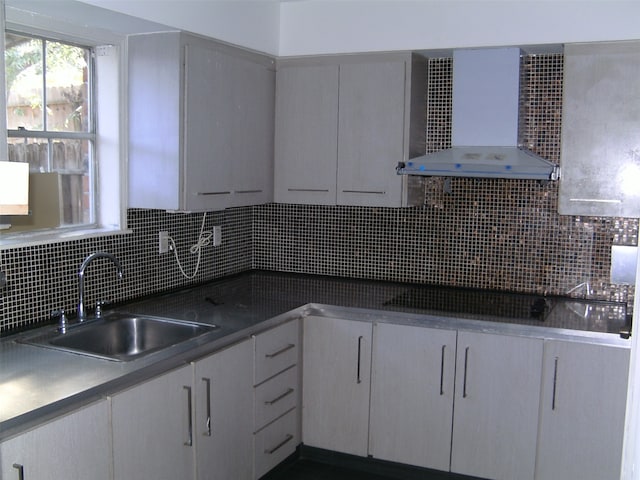 kitchen featuring backsplash, sink, and wall chimney range hood