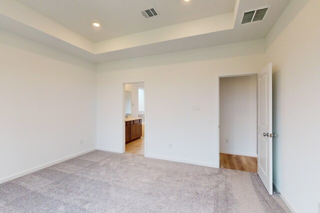 unfurnished bedroom with ensuite bathroom and light carpet