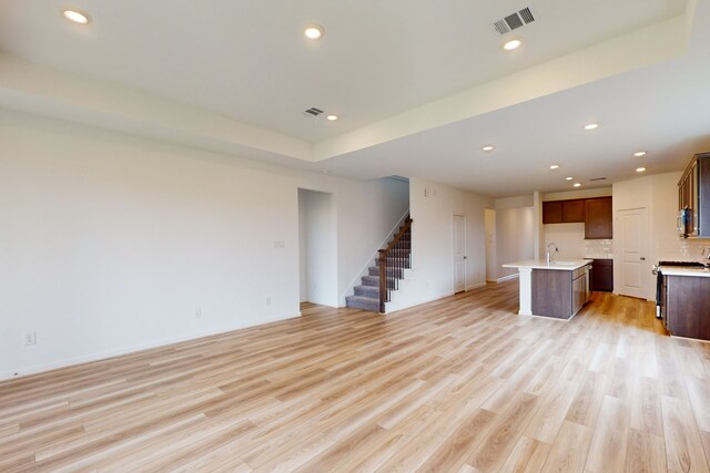 unfurnished living room with light hardwood / wood-style flooring and sink