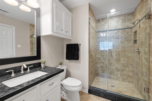 bathroom featuring vanity, toilet, a shower with shower door, and tile patterned flooring