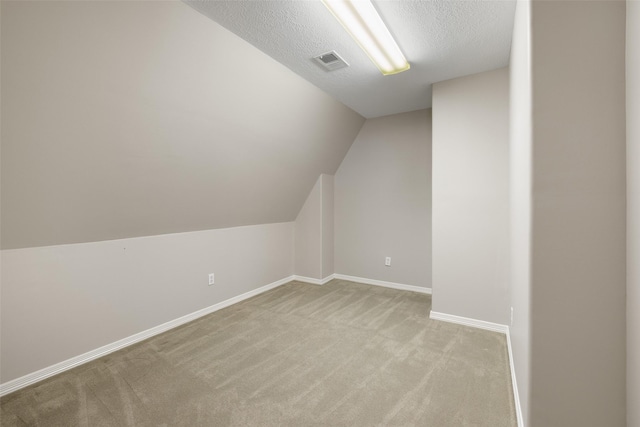 additional living space featuring light colored carpet, lofted ceiling, and a textured ceiling