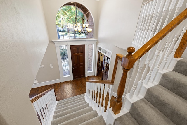 entryway featuring an inviting chandelier, a towering ceiling, and wood-type flooring