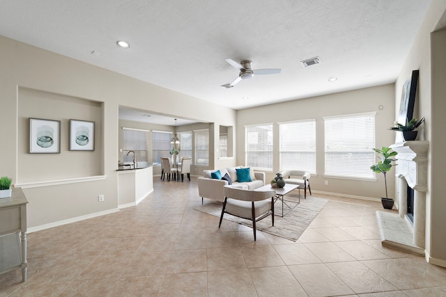 tiled living room with ceiling fan, sink, and a textured ceiling