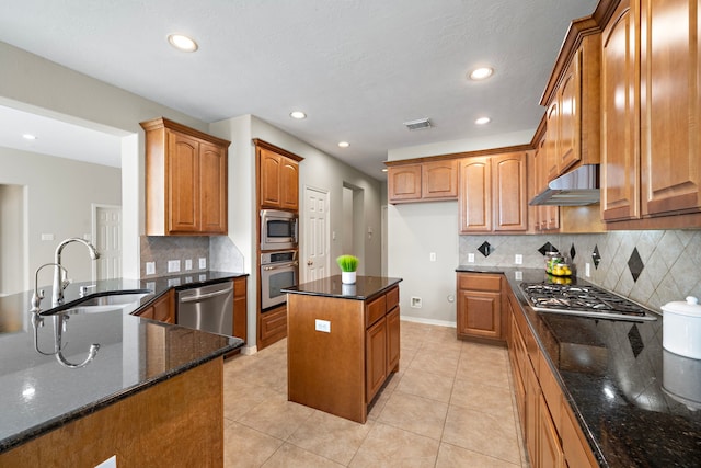 kitchen with a center island, dark stone counters, sink, light tile patterned floors, and appliances with stainless steel finishes