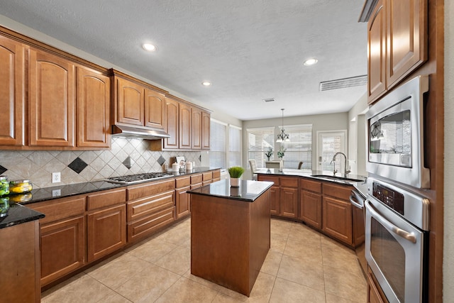 kitchen with stainless steel appliances, sink, decorative light fixtures, a center island, and light tile patterned flooring