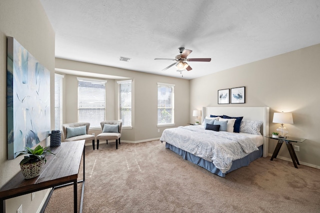 bedroom with ceiling fan, light colored carpet, and a textured ceiling