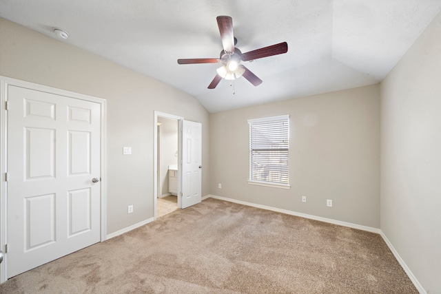 unfurnished bedroom with connected bathroom, ceiling fan, light colored carpet, and lofted ceiling