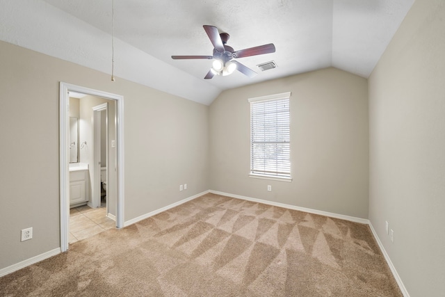 unfurnished bedroom with ceiling fan, lofted ceiling, light carpet, and ensuite bath