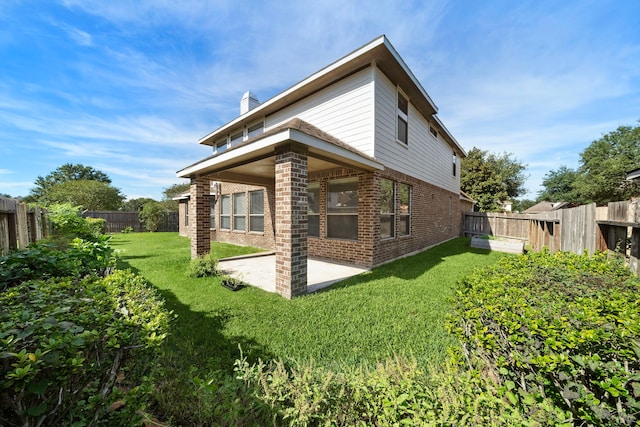 rear view of property featuring a lawn and a patio area