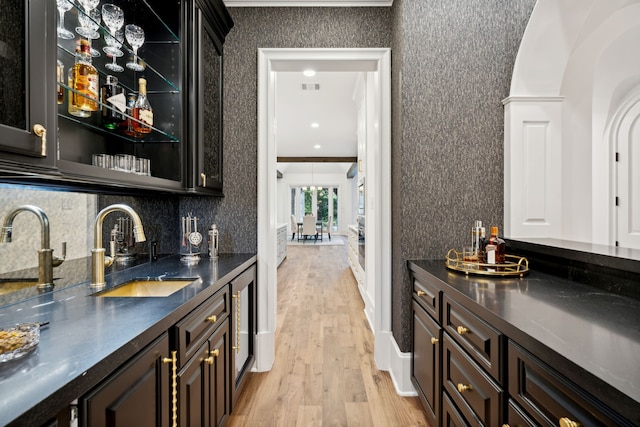 bar featuring crown molding, light hardwood / wood-style floors, sink, and decorative backsplash