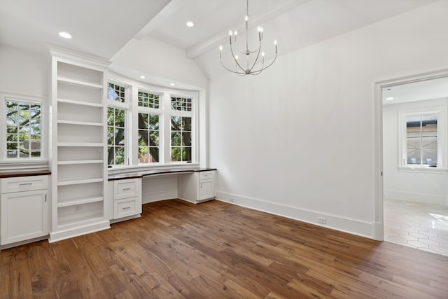 interior space featuring beam ceiling, built in desk, dark hardwood / wood-style floors, and a chandelier