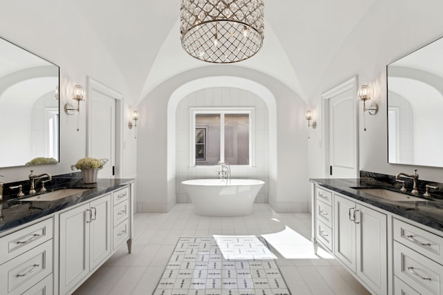 bathroom featuring lofted ceiling, vanity, tile patterned flooring, and a bathing tub