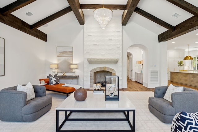 living room featuring beamed ceiling, high vaulted ceiling, a notable chandelier, and a fireplace