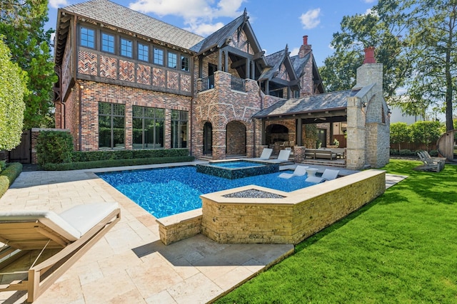 back of property featuring a balcony, a yard, a pool with hot tub, and a patio