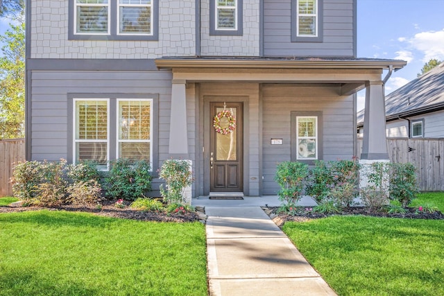 doorway to property featuring a yard and covered porch