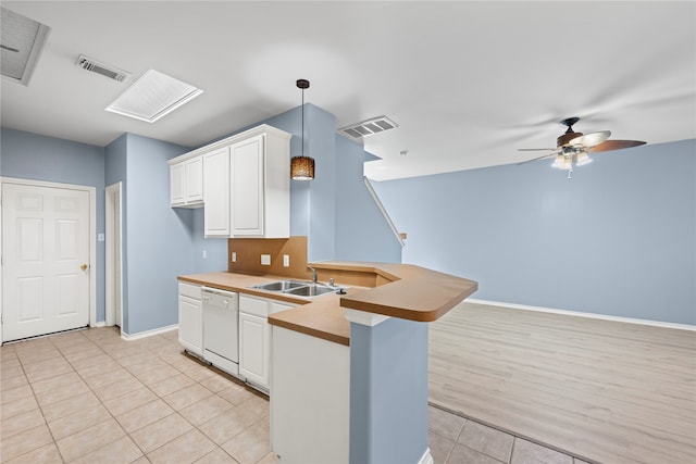 kitchen with kitchen peninsula, sink, dishwasher, white cabinetry, and hanging light fixtures