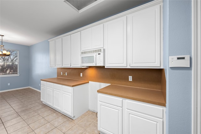 kitchen with white cabinets, hanging light fixtures, light tile patterned floors, and a notable chandelier