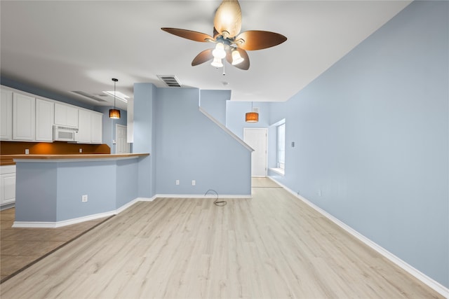 unfurnished living room featuring ceiling fan and light wood-type flooring