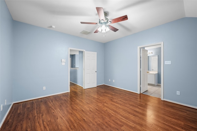 unfurnished bedroom featuring a walk in closet, vaulted ceiling, hardwood / wood-style flooring, ceiling fan, and connected bathroom