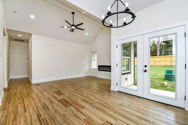 unfurnished living room with beam ceiling, light wood-type flooring, high vaulted ceiling, and french doors