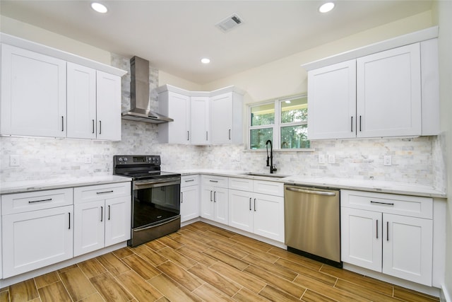 kitchen featuring white cabinets, stainless steel dishwasher, black / electric stove, and wall chimney range hood