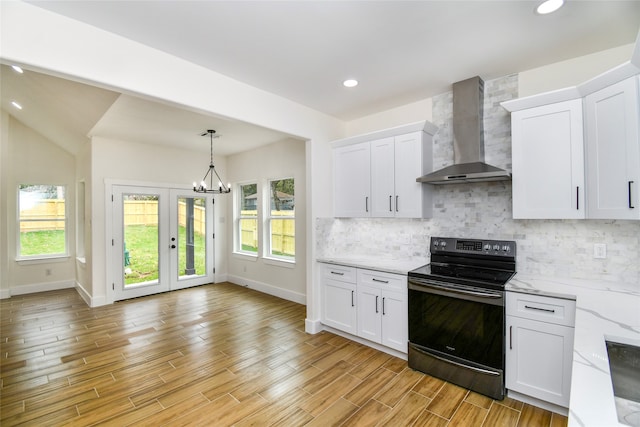 kitchen with light wood-type flooring, white cabinetry, black range with electric stovetop, and wall chimney exhaust hood