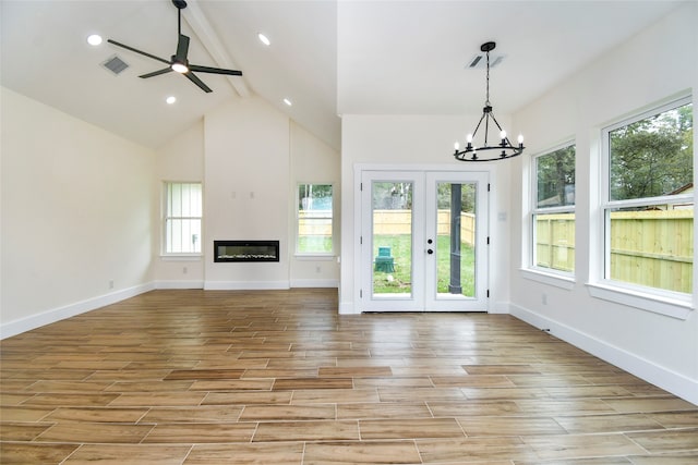 unfurnished living room with beamed ceiling, ceiling fan with notable chandelier, light hardwood / wood-style floors, and plenty of natural light