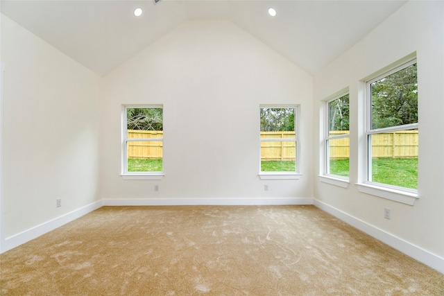 spare room featuring plenty of natural light, light carpet, and high vaulted ceiling