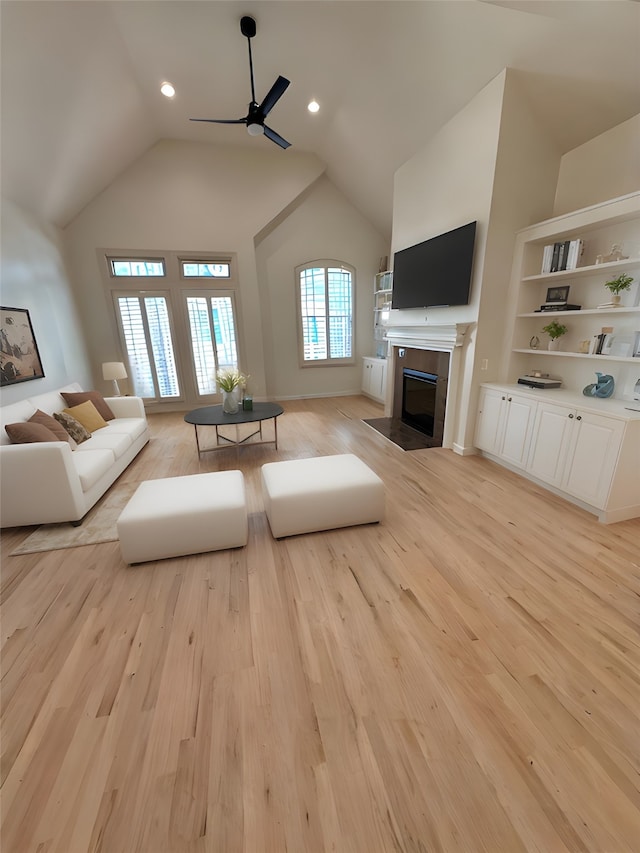 living room featuring ceiling fan, lofted ceiling, and light hardwood / wood-style flooring