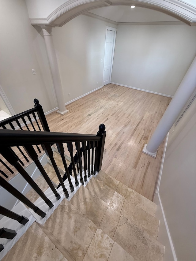 stairway with ornate columns, crown molding, and hardwood / wood-style floors