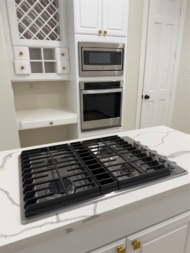 kitchen with light stone counters, white cabinets, and appliances with stainless steel finishes