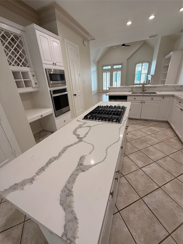 kitchen with ornamental molding, stainless steel appliances, ceiling fan, white cabinetry, and lofted ceiling