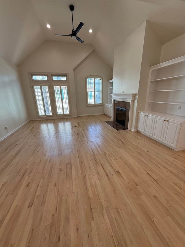 unfurnished living room featuring ceiling fan, light hardwood / wood-style floors, built in shelves, and vaulted ceiling