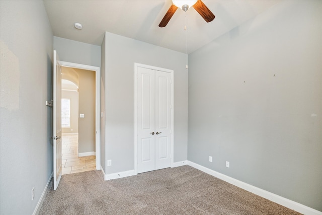 unfurnished bedroom featuring ceiling fan, a closet, and light colored carpet