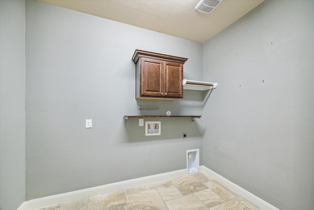 clothes washing area with hookup for a washing machine, cabinets, a textured ceiling, and hookup for an electric dryer