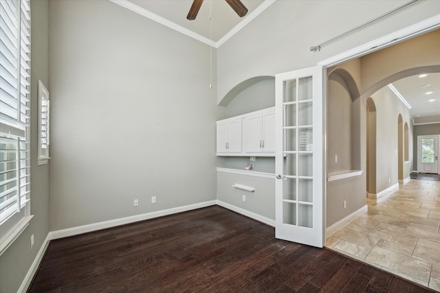 spare room featuring ceiling fan, french doors, a high ceiling, wood-type flooring, and ornamental molding