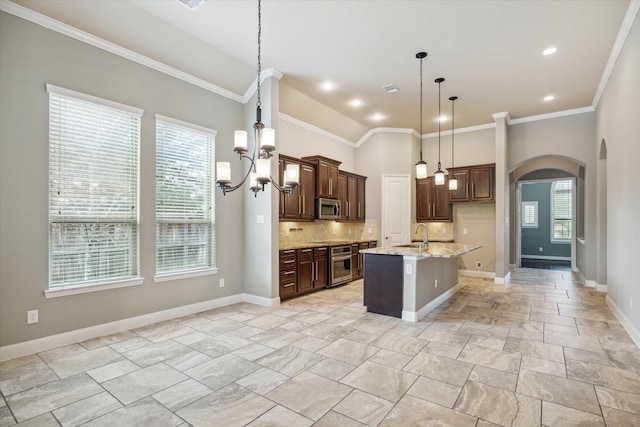 kitchen featuring decorative backsplash, crown molding, an island with sink, and appliances with stainless steel finishes