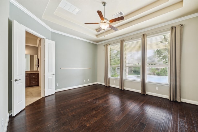 unfurnished room featuring a raised ceiling, dark wood-type flooring, and crown molding