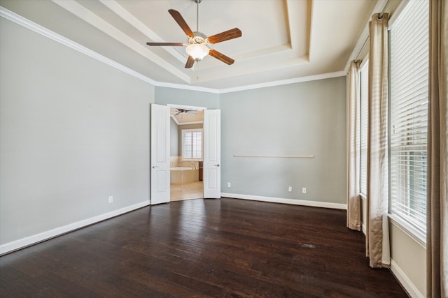 unfurnished room featuring a tray ceiling, crown molding, ceiling fan, and dark wood-type flooring