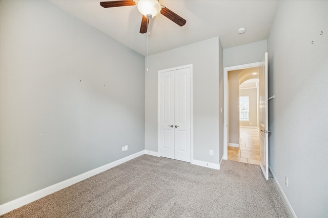 unfurnished bedroom with ceiling fan, light colored carpet, and a closet